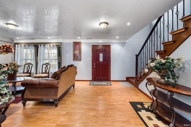 foyer entrance featuring crown molding and light wood-type flooring