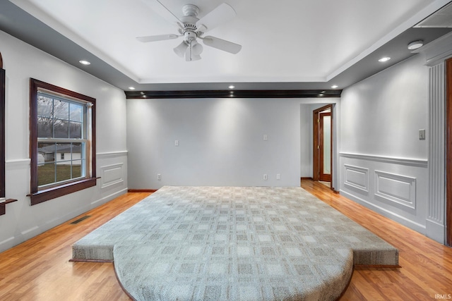 spare room featuring a raised ceiling, ceiling fan, and light hardwood / wood-style flooring