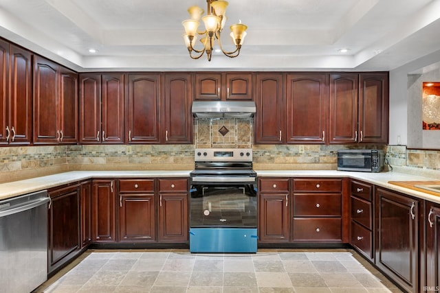 kitchen with a tray ceiling, backsplash, stainless steel appliances, and a notable chandelier