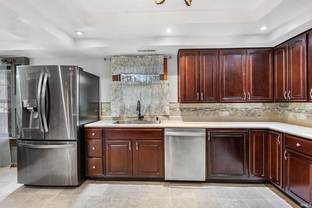 kitchen with backsplash, stainless steel appliances, a tray ceiling, sink, and light tile patterned floors