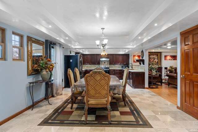 dining area with a tray ceiling, an inviting chandelier, and light hardwood / wood-style floors