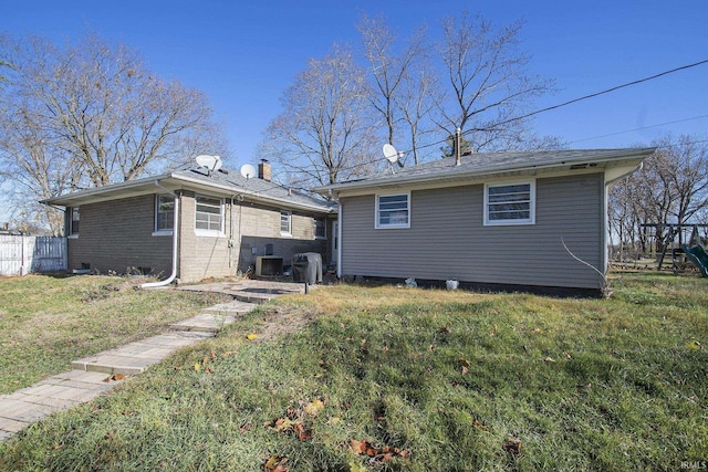 rear view of property featuring a lawn and central air condition unit