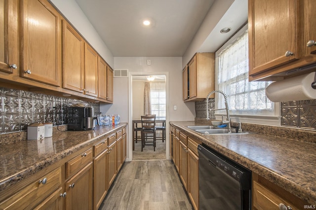 kitchen featuring wood-type flooring, black dishwasher, tasteful backsplash, and sink