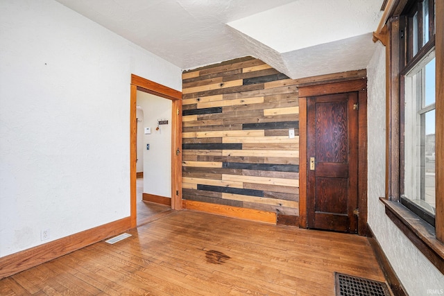 foyer entrance featuring hardwood / wood-style flooring and wooden walls