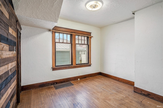 unfurnished room with a textured ceiling and hardwood / wood-style flooring