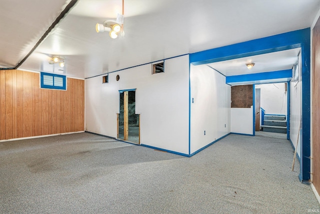 carpeted spare room featuring wood walls