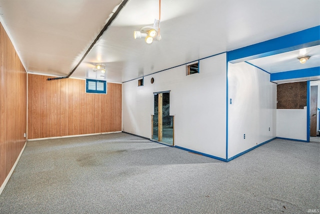 carpeted empty room featuring a notable chandelier and wood walls