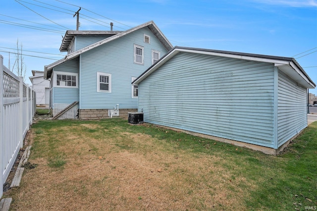 back of house featuring central AC unit and a lawn