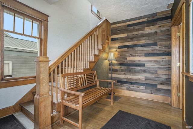 stairway with wood-type flooring, a textured ceiling, and wooden walls