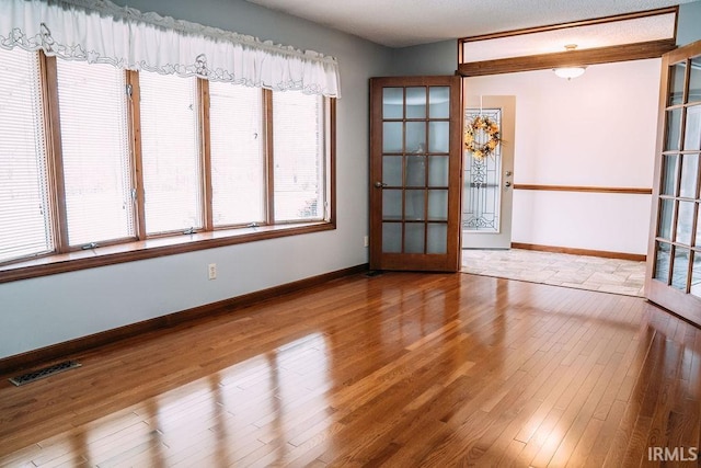 unfurnished room featuring french doors and light wood-type flooring