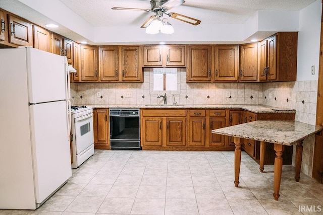 kitchen featuring white appliances, sink, ceiling fan, light tile patterned floors, and a textured ceiling