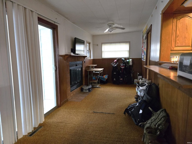 interior space with ceiling fan, wood walls, and carpet floors