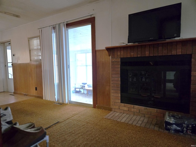 carpeted living room featuring wood walls and a brick fireplace