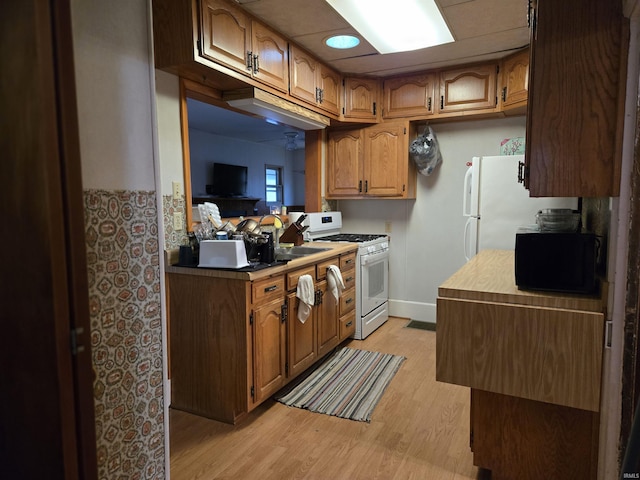 kitchen with light hardwood / wood-style flooring, white appliances, and sink