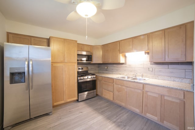 kitchen with backsplash, sink, ceiling fan, light wood-type flooring, and appliances with stainless steel finishes