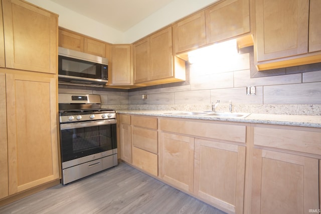 kitchen with light brown cabinetry, sink, stainless steel appliances, and light wood-type flooring