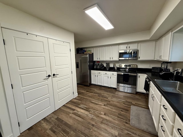 kitchen featuring dark hardwood / wood-style flooring, white cabinetry, sink, and appliances with stainless steel finishes