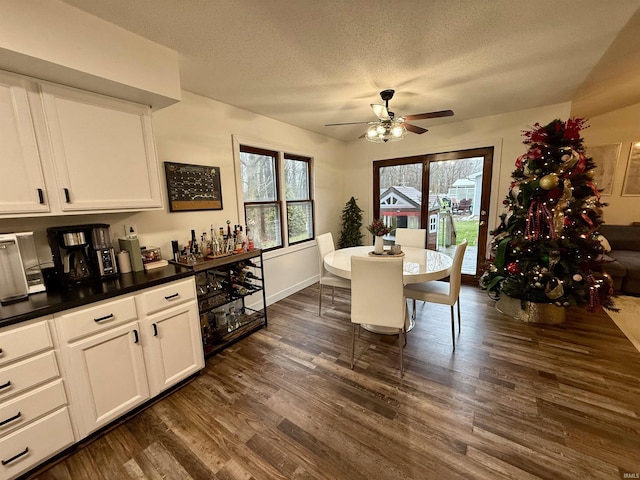 dining room with a textured ceiling, ceiling fan, and dark wood-type flooring