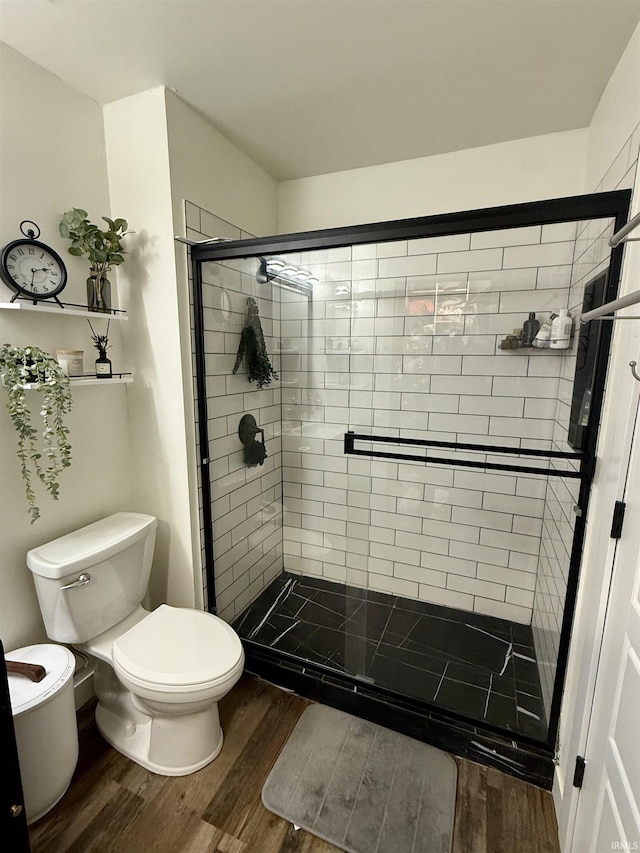 bathroom featuring toilet, a shower with shower door, and hardwood / wood-style flooring