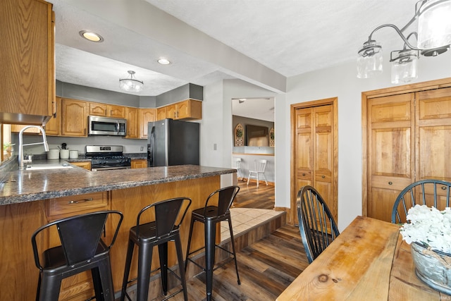 kitchen featuring sink, a textured ceiling, appliances with stainless steel finishes, dark hardwood / wood-style flooring, and kitchen peninsula