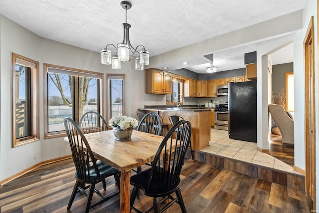 dining area with a textured ceiling, an inviting chandelier, and light hardwood / wood-style flooring