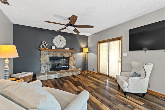 living room featuring a textured ceiling, ceiling fan, dark hardwood / wood-style flooring, and a fireplace