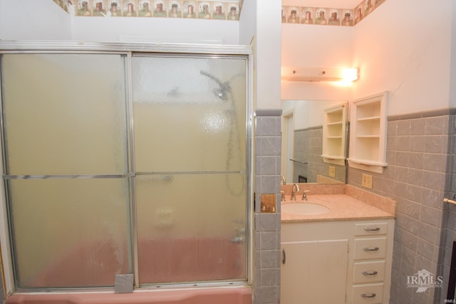 bathroom featuring vanity, a shower with shower door, and tile walls