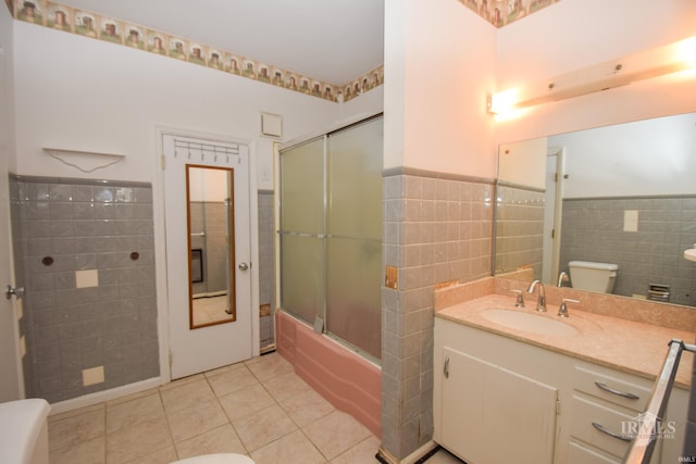 full bathroom featuring tile patterned floors, toilet, bath / shower combo with glass door, and tile walls