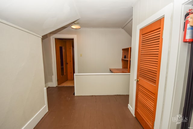 hallway with dark wood-type flooring and vaulted ceiling