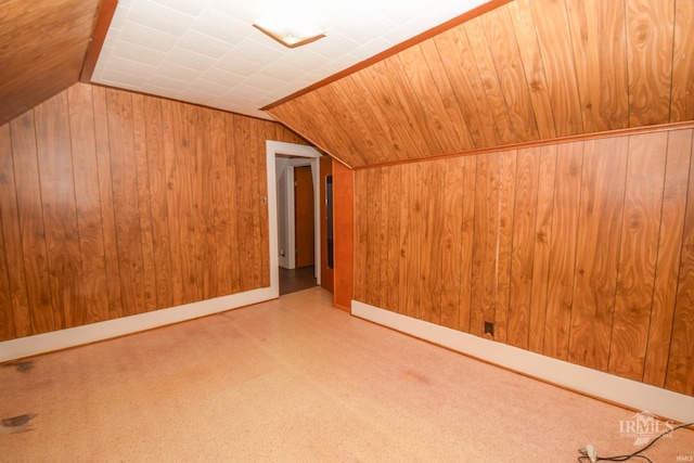 bonus room with wooden walls and vaulted ceiling