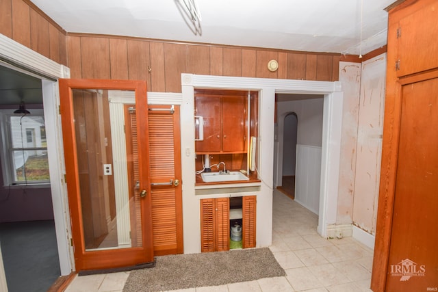 interior space with wood walls, light tile patterned floors, and sink