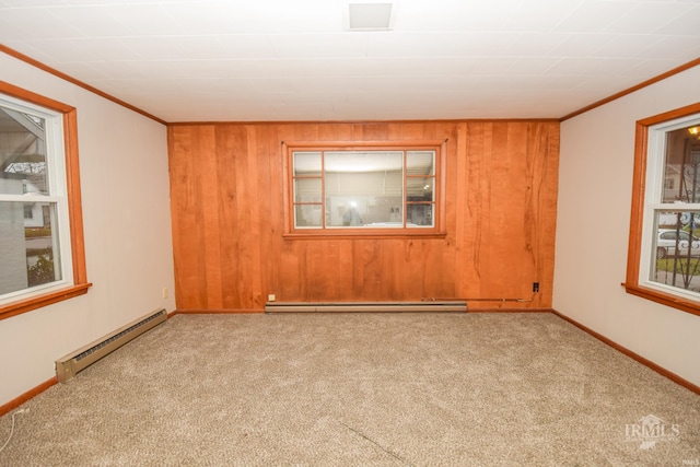 carpeted empty room with wood walls, crown molding, and a baseboard heating unit