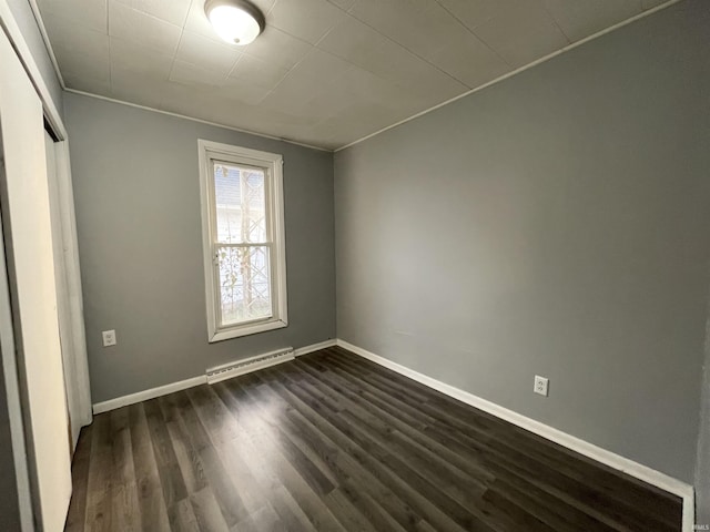 unfurnished bedroom featuring baseboard heating, a closet, and dark wood-type flooring