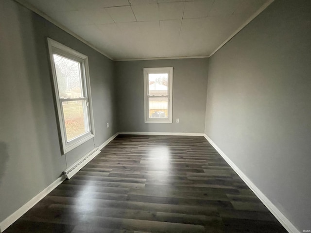 spare room with plenty of natural light, crown molding, dark wood-type flooring, and a baseboard heating unit