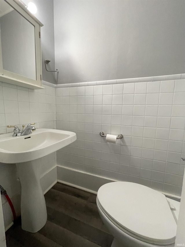 bathroom with sink, wood-type flooring, tile walls, and toilet