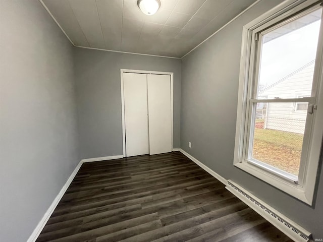 unfurnished bedroom with a closet, dark hardwood / wood-style flooring, crown molding, and a baseboard radiator