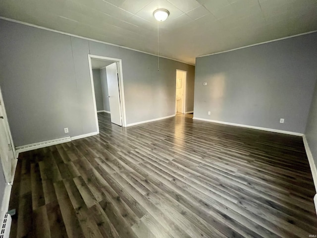 empty room with baseboard heating and dark hardwood / wood-style floors