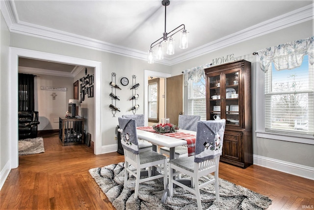 dining space featuring wood-type flooring, ornamental molding, and an inviting chandelier