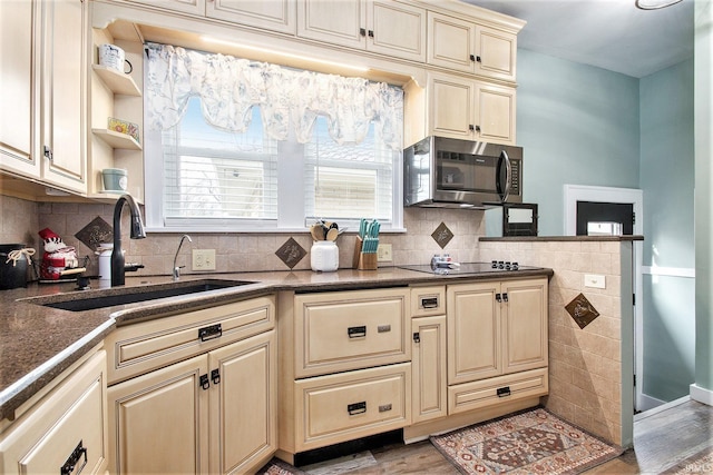 kitchen with tasteful backsplash, black electric cooktop, sink, and light wood-type flooring