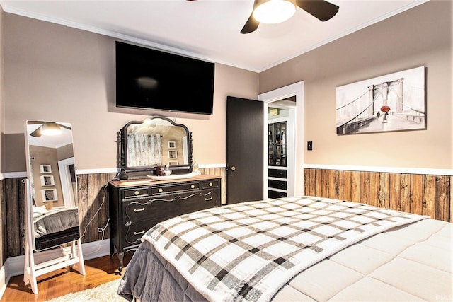 bedroom featuring ceiling fan, crown molding, wooden walls, and light hardwood / wood-style flooring