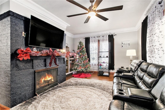 living room featuring a fireplace, ceiling fan, wood-type flooring, and ornamental molding