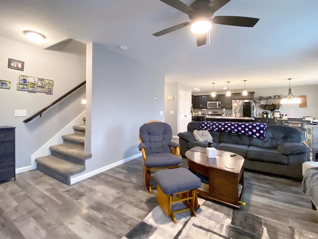 living room featuring dark hardwood / wood-style flooring and ceiling fan with notable chandelier