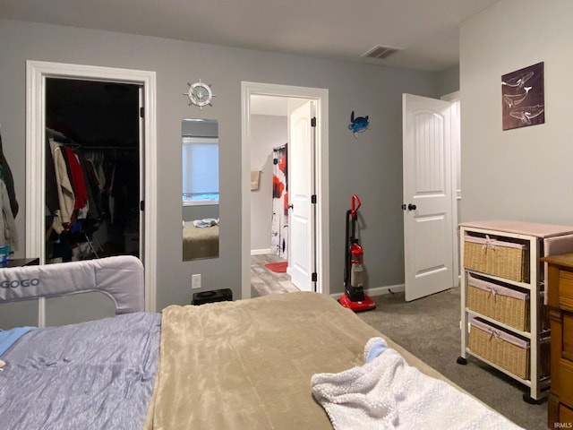 bedroom featuring ensuite bathroom, dark carpet, a walk in closet, and a closet