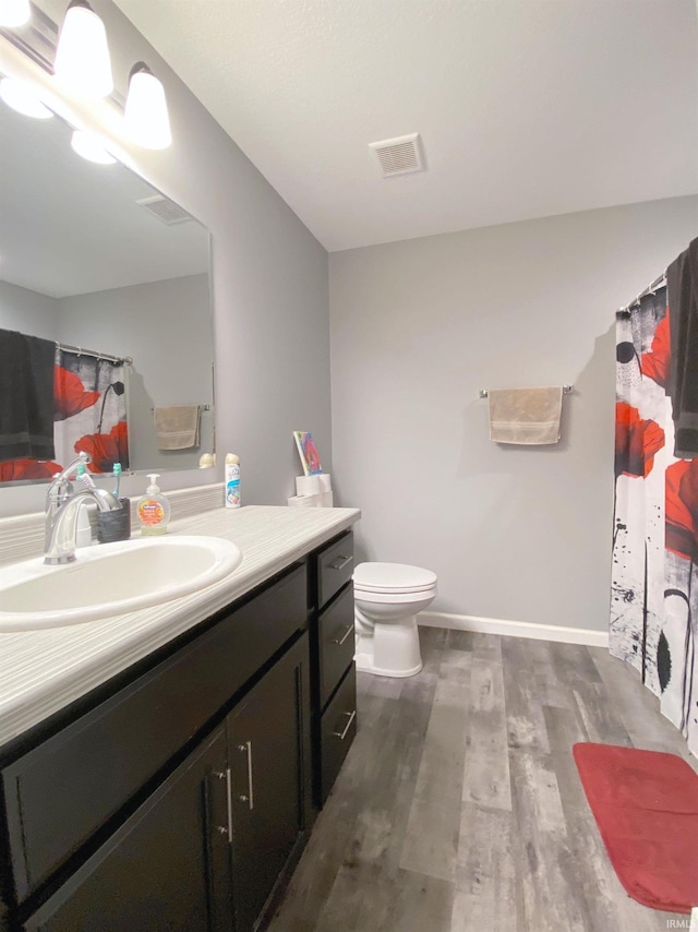 bathroom featuring wood-type flooring, vanity, and toilet