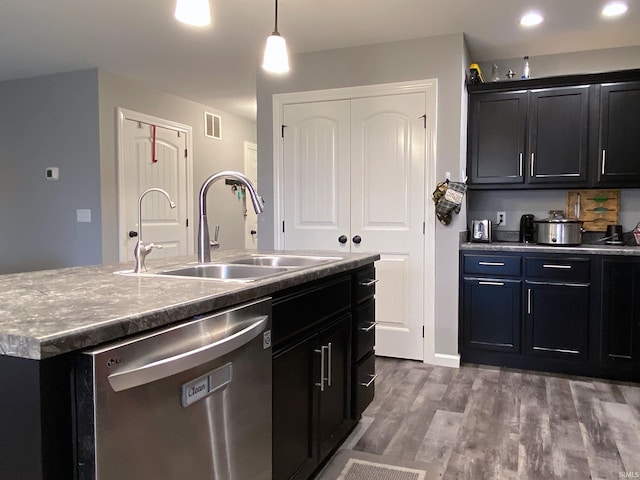 kitchen with dishwasher, a kitchen island with sink, sink, hanging light fixtures, and hardwood / wood-style flooring