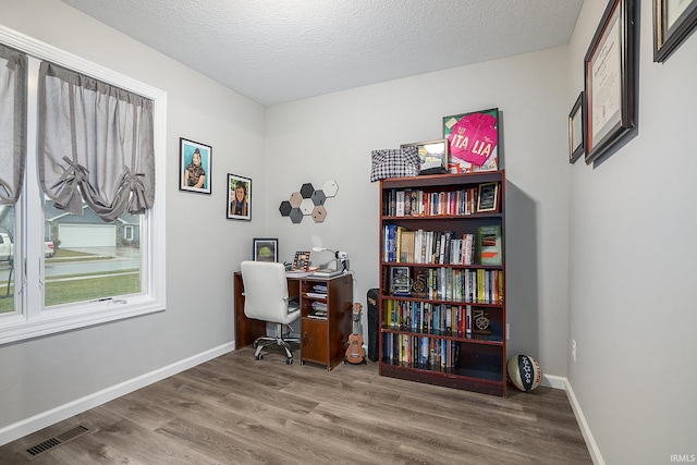 home office featuring wood-type flooring and a textured ceiling