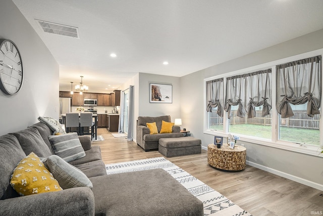 living room with light hardwood / wood-style floors and an inviting chandelier