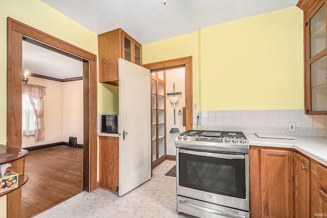 kitchen with decorative backsplash, light hardwood / wood-style flooring, and stainless steel gas range oven