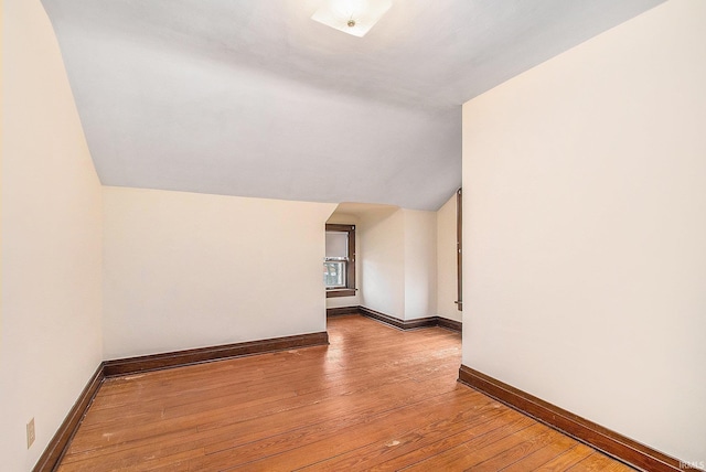 spare room with vaulted ceiling and light hardwood / wood-style flooring