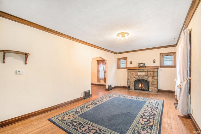 living room with crown molding, a fireplace, light hardwood / wood-style floors, and a textured ceiling